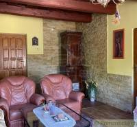 Living room of a family house with leather armchairs, a stove, and wooden ceiling beams.