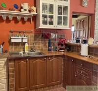 A kitchen in a family house with wooden furniture and an orange wall.