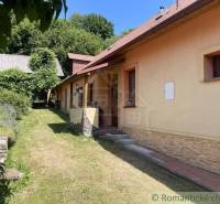 A family house in Medzev with a lawn, surrounded by trees and a hedge.