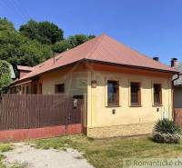 A family house in Medzev with a brown roof and a wooden fence on Green Street.