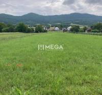 The image shows a green meadow on Jasenovská Street towards the playground, ideal for residential plots.