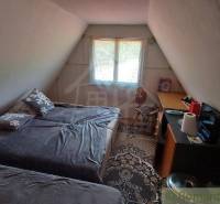The attic room in the cottage with two beds, a table, and a window exudes coziness.