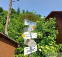 A signpost near the cottage by Myjava, surrounded by greenery and wooden structures.