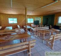 A cabin with wooden benches, tables, and a sofa; the stove adds coziness.