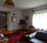 Living room with a sofa, television, armchair, and curtains in a family house.
