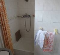 A bathroom in a family house with tiles, a shower, and towels on a rack.