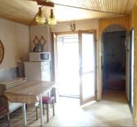 Interior of a family house with a table, chairs, and a refrigerator next to a microwave.