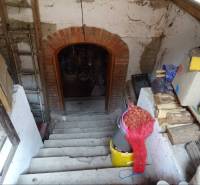 A staircase in the basement of a family house with supplies of wood and cardboard boxes.