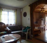 Living room in a family house with rattan chairs, a sofa, and a view of the kitchen.
