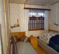 Bedroom in a family house with beds and patterned wallpaper.