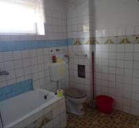 Bathroom with a bathtub, toilet, and rectangular tiles in a family house.