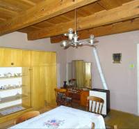 The dining room of a family house with a wooden ceiling, furniture, and tiles.