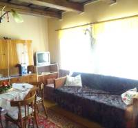 A living room in a family house furnished with wooden furniture, a television, and a dining table.