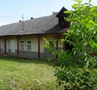 An older family house in Tornaszentandrás with a grassy garden and a covered veranda.