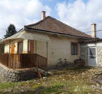 A family house in Füzérkomlós with a gable roof, a stone annex, and a picket fence.