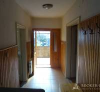 Entrance hall in a family house with wooden paneling and open doors to the porch.