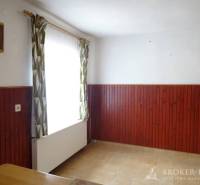 Room in a family house with wooden paneling, curtains, and a wall clock.
