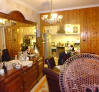 A dining room in a family house with wooden furniture and mirrors, overlooking the kitchen.