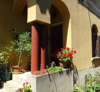 A family house in Encs with columns and flowers at the entrance on a sunny terrace.