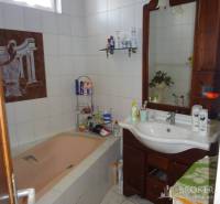 A bathroom in a family house with a bathtub, mirror, and wooden sink.
