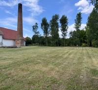 A chimney and a building on a grassy plot in Zemianske Sady on Zemianske Sady Street, warehouses and halls.