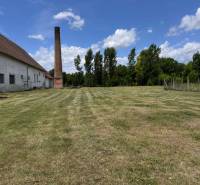 A grassy plot with a chimney and a building in Zemianske Sady near Zemianske Sady Street, warehouses and halls.