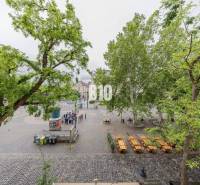 A historic square surrounded by trees with empty café tables, Bratislava - Old Town.