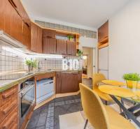 Kitchen corner with wooden cabinets and a dining table in a 2-room apartment.