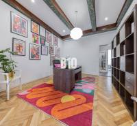 A stylish office in a 2-room apartment with a desk, shelves, and colorful paintings on the wall.