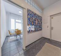 Entrance hall in a 2-room apartment with a colorful painting and a view into the dining room with chairs.