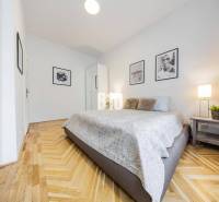 A bedroom in a 2-room apartment with patterned flooring and artistic photographs on the walls.