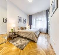 A bright room in a 2-room apartment with wooden flooring, a mirror, and decorative pictures.