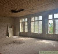 An empty room in a family house with large windows and leaning doors.