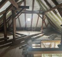 Attic in a family house with wooden beams and a hole in the floor.