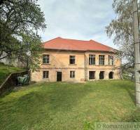 A family house in Rimavská Sobota with a red roof, situated among trees and grass.