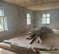 An older room of a family house with an exposed brick wall and wooden planks on the floor.