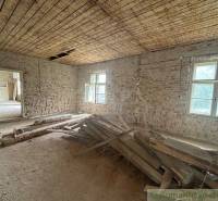 A shabby room with exposed bricks and a pile of wood in a family house.
