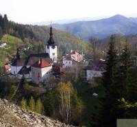Gardens in Banská Bystrica depict a picturesque village with a church surrounded by forests and mountains.