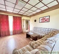 Living room with a striped sofa, wooden floor, and burgundy curtains in a family house.