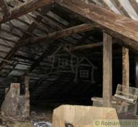 Attic in a family house with wooden beams and a chimney.