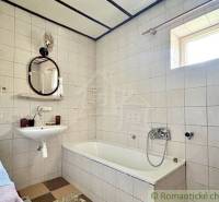 A bathroom in a family house with white tiles, a bathtub, and a sink.