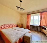 A bedroom with two beds and orange curtains in a family house.