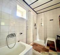 A bathroom in a family house with a shower, a bathtub, and a shelf.