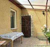A family house in Gemerská Hôrka with a terrace, table, chairs, and blooming roses.