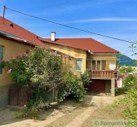 A family house in Gemerská Hôrka with flowers and a balcony, surrounded by greenery.