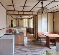 A kitchen in a family house with a stove, wooden seating, and indoor lamps.