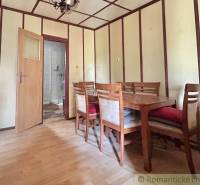 A dining room with wooden furniture and open doors in a family house.
