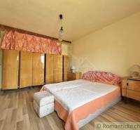 A bedroom in a family house with a large bed, wardrobes, and wooden furniture.