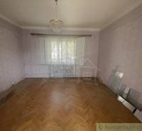 A room in a family house with a parquet floor, a chandelier, and lace curtains.