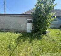 A family house in Nové Zámky with greenery and a white building on the property.